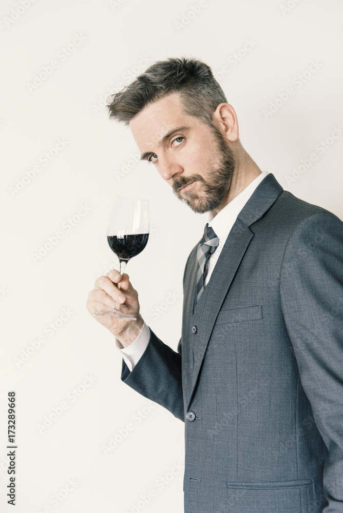 Handsome man holding red wine glass wearing a nice suit looking at the camera Handsome man holding red wine glass wearing a nice suit looking at the camera