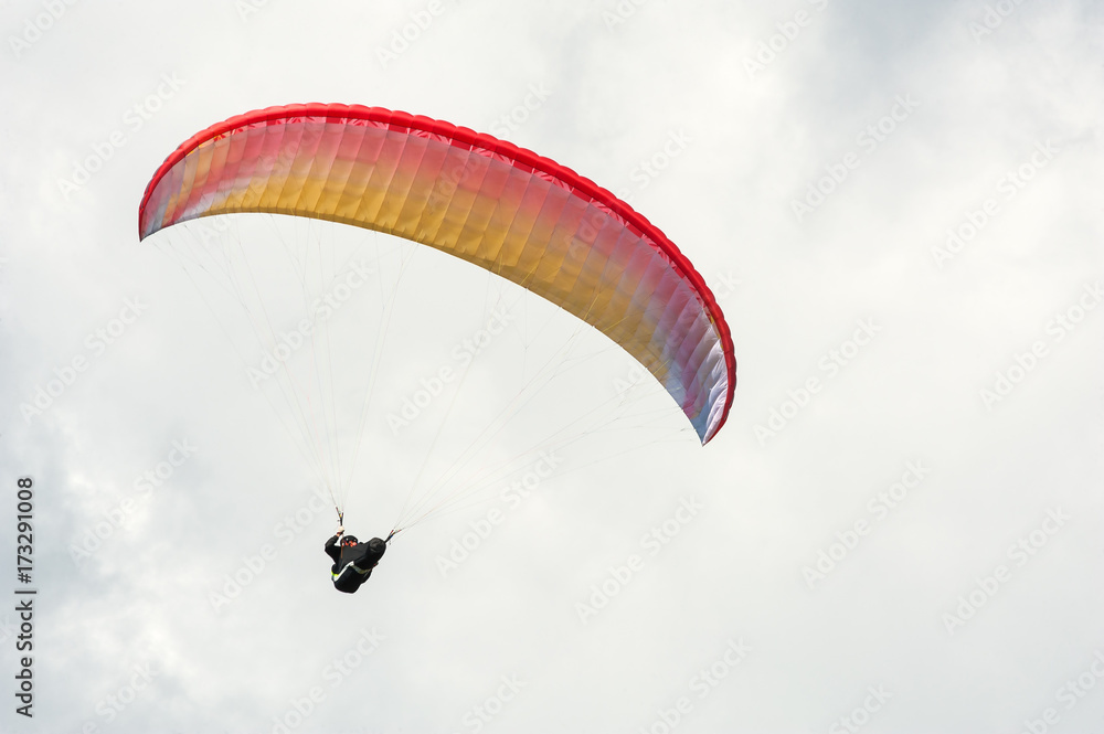 Paraglider flying in the blue sky against the background of clouds. Paragliding in the sky on a sunny day. Paraglider flying in the blue sky against the background of clouds. Paragliding in the sky on a sunny day.