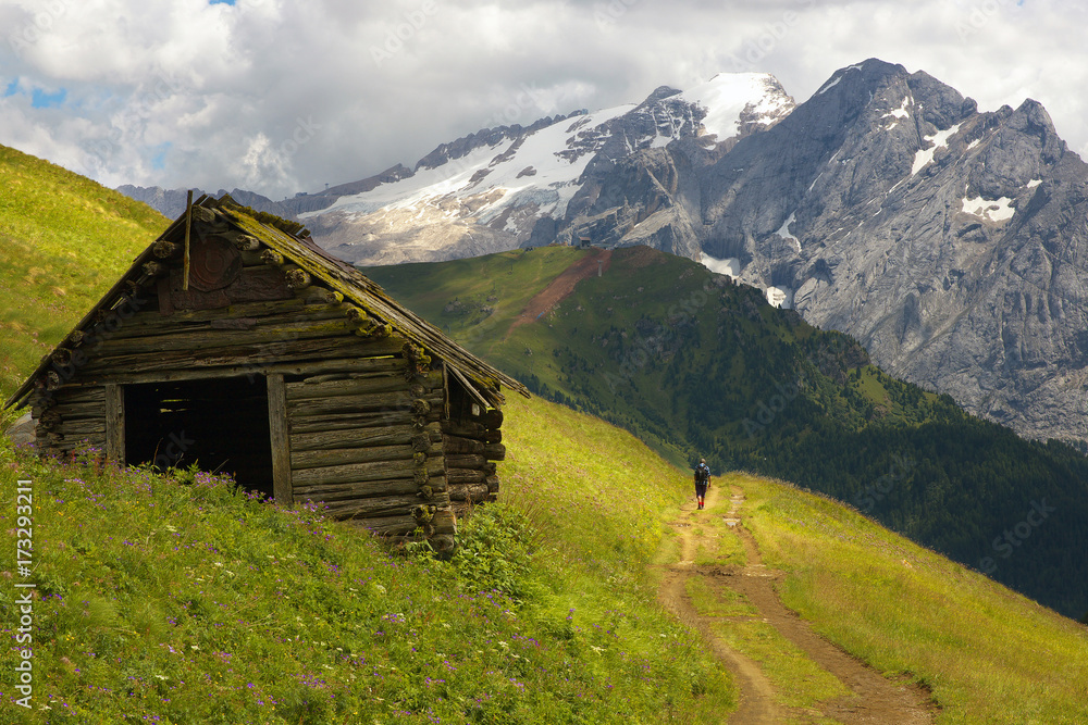 Old cabin in Dolomites with Marmolada peak on the background, Italy