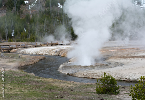 Venting geyser next to flowing stream