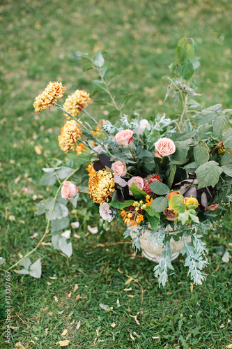 arranging, nature, gardening concept. on the green grass there is stunning bunch of flowers in the vase created with little pink roses and great orange chrisantemums by professional florist photo