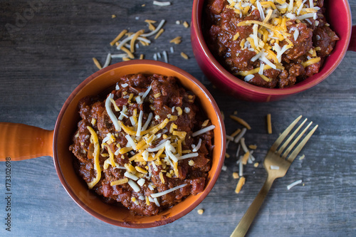 two colorful bowls of chilli with chedder cheese top view photo