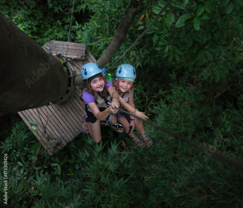 Two little girls rappelling from a tree