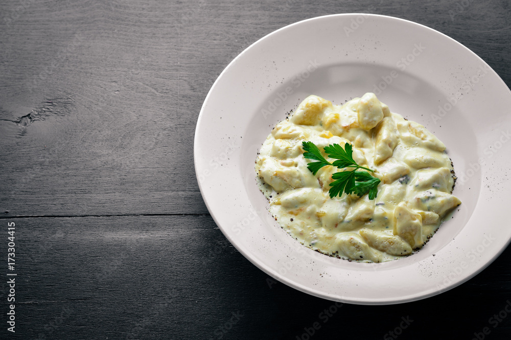 Dumpling from potatoes under cheese sauce. On a wooden background. Top view. Free space. Dumpling from potatoes under cheese sauce. On a wooden background. Top view. Free space.