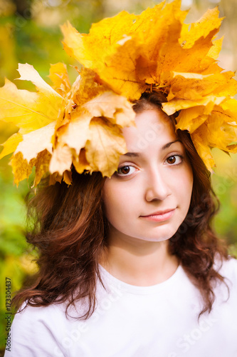 fall, beauty, femininity cincept. very cute caucasian young girl with delicate round face, big stunning brown eyes and nice curly hair, she is wearing autumnal wreath of yellow leaves of maple