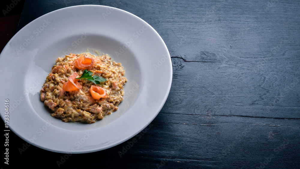 Risotto with salmon and cream sauce. On a wooden background. Top view. Free space.