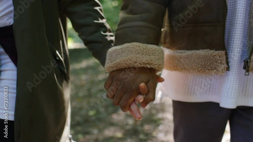 Close up of a couple holding hands as they walk in a forest photo