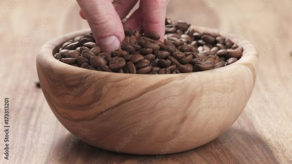Slow motion young man hand taking some coffee beans from bowl to check quality Slow motion young man hand taking some coffee beans from bowl to check quality