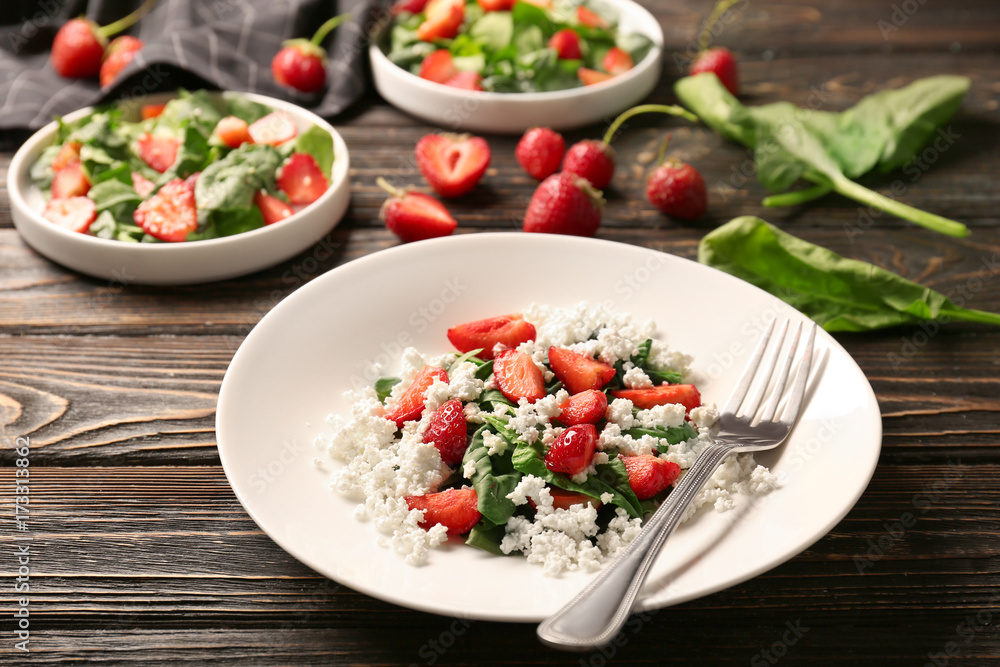 Plate with strawberry spinach salad on wooden table Plate with strawberry spinach salad on wooden table