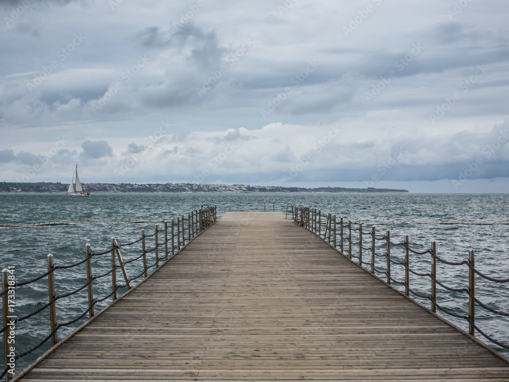 Pier in the sea against a background of clouds