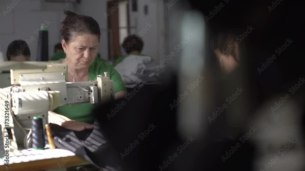 Tailoring close up,thread old sewing machine in focus, tailor stitching fabric textile in the blurred background, shallow depth of field, concept workshop, interior scene Tailoring close up,thread old sewing machine in focus, tailor stitching fabric textile in the blurred background, shallow depth of field, concept workshop, interior scene