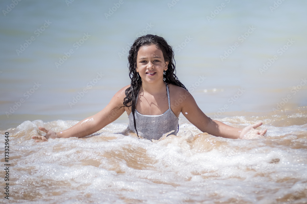 Fototapeta premium Niña morena bañándose en el mar y jugando con las olas.