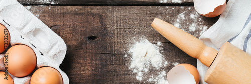 Baking or cooking wooden background with cookies molds, flour, milk, kitchen tools and eggs, top view