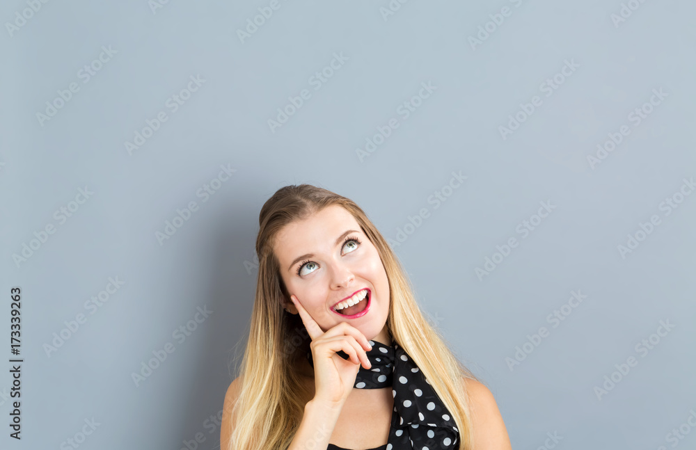 Fototapeta premium Young woman in a thoughtful pose on a gray background