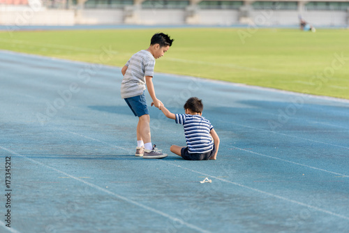 Boy help each other on blue track after fall