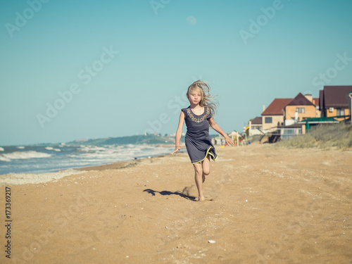 The girl in the gray dress with her hair running on the sand.