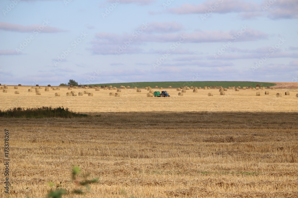 in the field the tractor collects the hay and twists it into rolls - a round stack