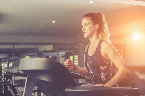 Young caucasian woman doing exercise with exercise equipment and machine in gym. Health and fitness concept.