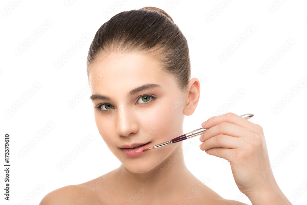 Fototapeta premium Portrait of beautiful young brunette woman with clean face. Beauty spa model girl with perfect fresh clean skin applying cosmetic brush. Youth and skin care concept. Isolated on a white background.