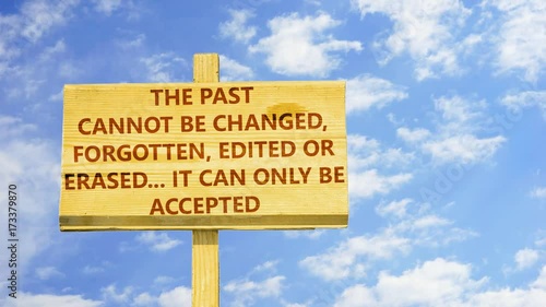 The past can not be changed, forgotton, edited of erased. It can only be accepted. Words on a wooden sign against time lapse clouds in the blue sky.  photo