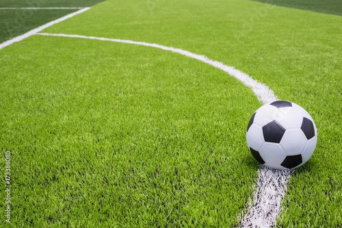 Soccer ball on artificial bright and dark green grass at public outdoor football or futsal stadium