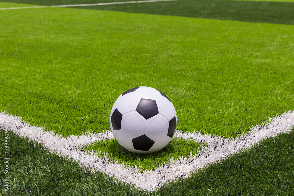 Fototapeta premium Piłka do piłki nożnej na sztucznej jasnej i ciemnozielonej trawie na publicznym stadionie piłki nożnej lub futsalu