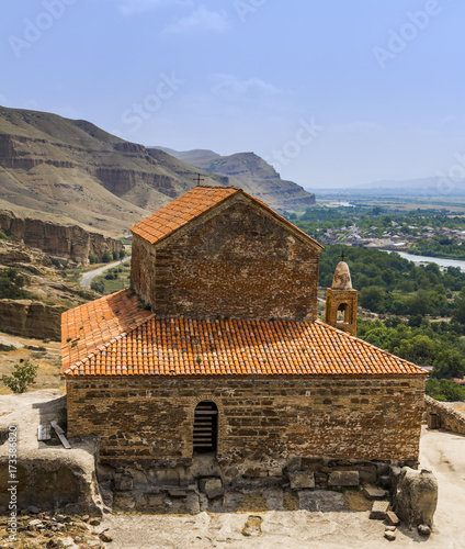 An old stone church on top of a mountain with a beautiful view.