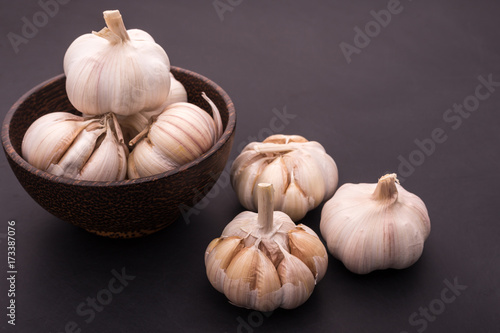 Garlic in dark bowl on black wooden table