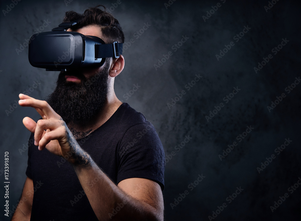 A man with tattoos on arms wearing VR glasses.