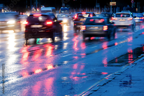 city road during rain. cars driving on wet road with headlights.