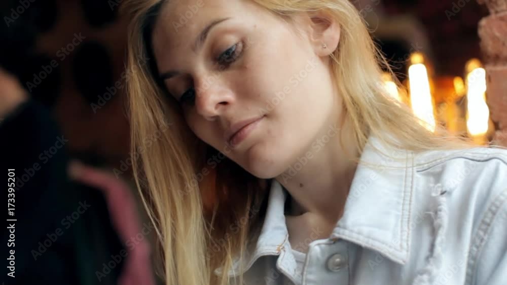 Beautiful Woman Uses a Phone While Sitting in a Cafe Beautiful Woman Uses a Phone While Sitting in a Cafe