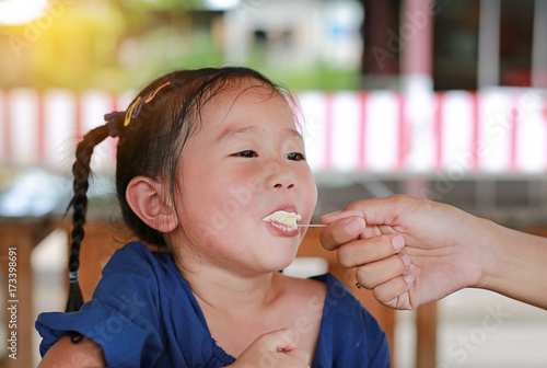 Mother feeding ice cream to her daughter. Little asian girl enjoy eating icecream with mother.