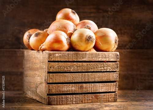 fresh raw onions in a wooden box