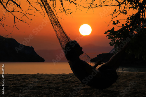 Silhouette of a woman relaxing on the beach with hammock