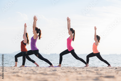 Yoga class at sea beach in evening ,Group of people doing Warrior poses with clam relax emotion at beach,Meditation pose,Wellness and Healthy balance lifestyle.