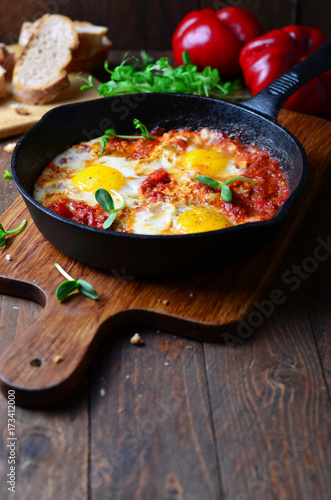 Shakshuka, Fried Eggs with Tomato Sauce in a Pan, Rustic Style and Wooden Background