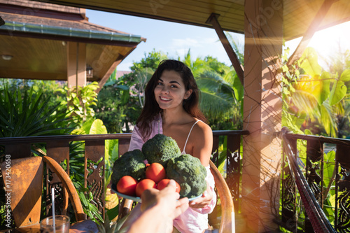 Male Hand Giving Beautiful Woman Plate Of Fresh Vegetables Pov Girl Happy Smiling Sit On Summer Terrace In Tropical Forest Organic Food And Nutrition Concept photo