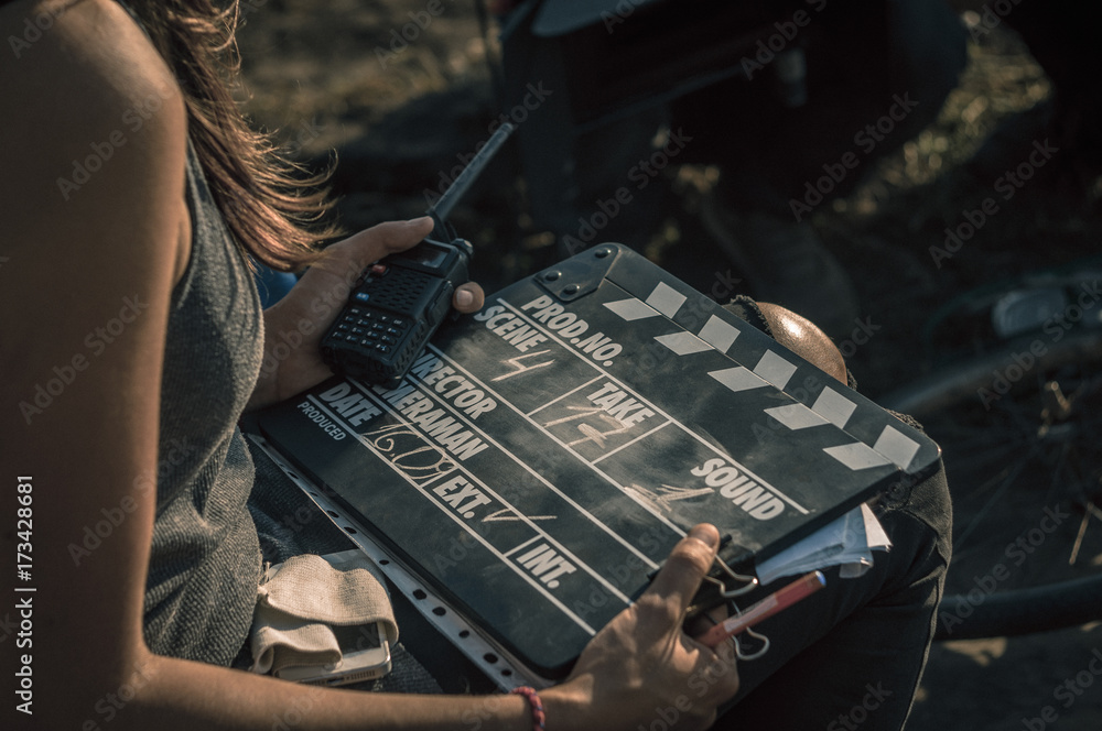 Fototapeta premium Woman holding clapperboard against her face