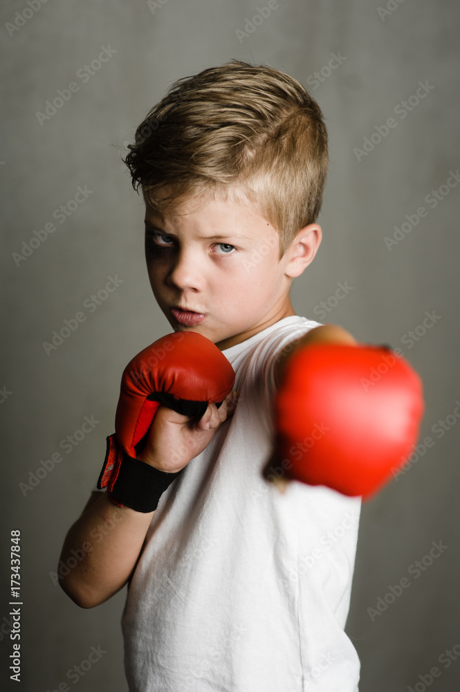 Beaten young boy punching with red boxing gloves Beaten young boy punching with red boxing gloves