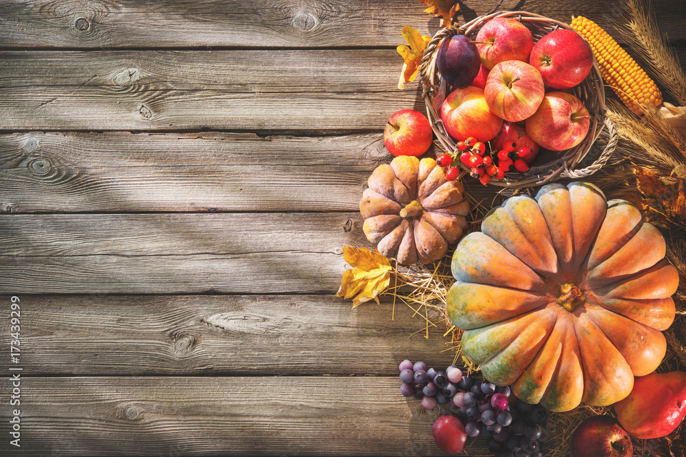 Thanksgiving background with pumpkins and falling leaves on rustic wooden table Thanksgiving background with pumpkins and falling leaves on rustic wooden table