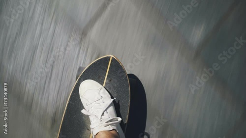 Top view handheld shot of man in white sneakers or skaters shoes rides longboard on asphalt or city tarmac photo