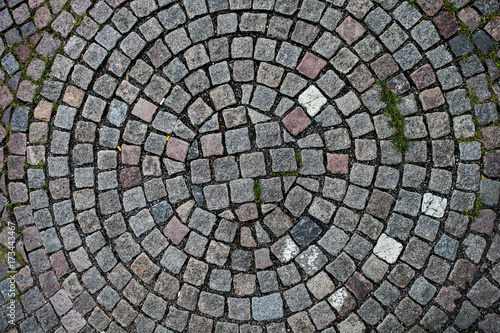 Cobblestones laid out in the shape of a circle seen from above. Perfect to use as a patterned background.