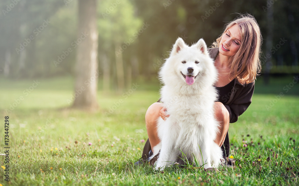 Portrait of smiling girl with her dog at park outdoor, samoyed