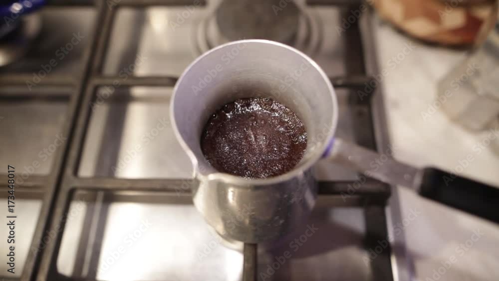 Turkish coffee boiling over from cezve. Dense foam in an aluminum coffee maker on a gas stove
