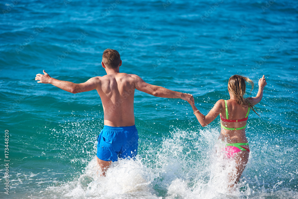 Caucasian man and woman running into the sea water. Back view. Caucasian man and woman running into the sea water. Back view.