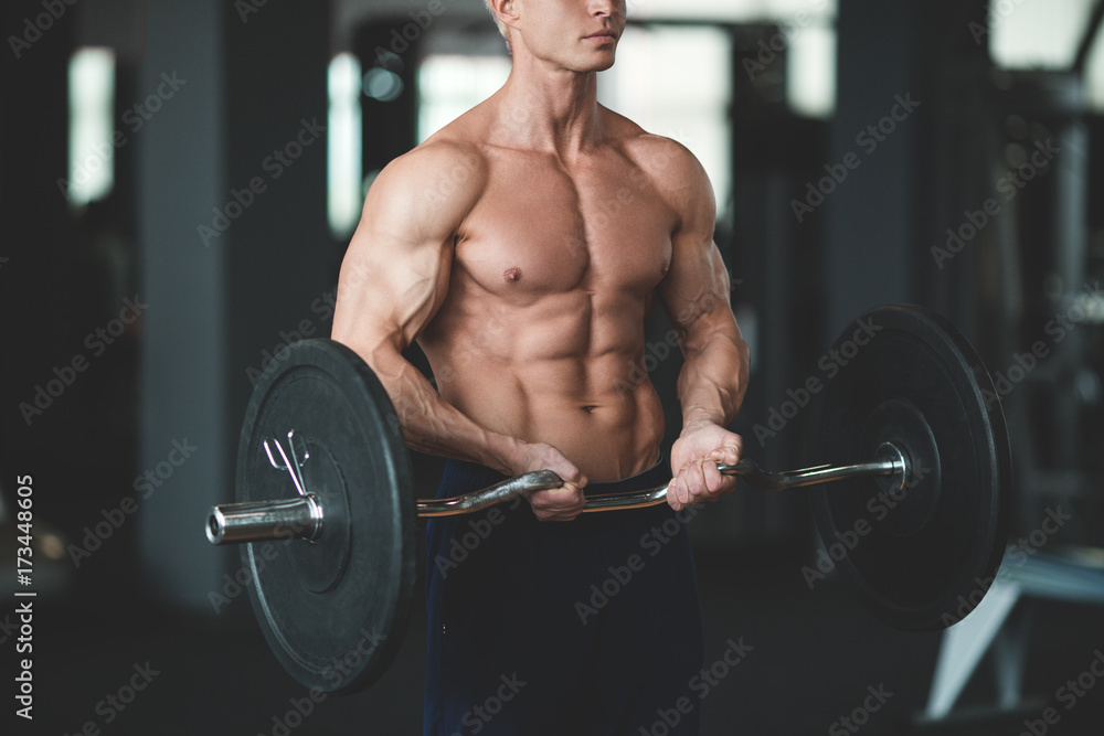 Strong man with muscular body working out in gym. Weight exercise with barbell in fitness club. Toned image Strong man with muscular body working out in gym. Weight exercise with barbell in fitness club. Toned image