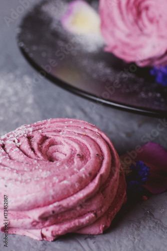 sweets and desserts, soft, airy and sweet pink currant or berry marshmallows with powdered sugar on a gray background