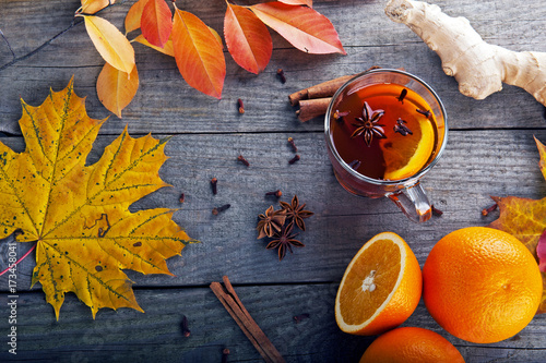hot tea with spices and orange amid autumn leaves