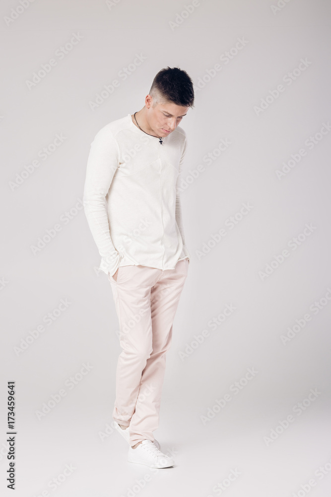 handsome young man in a white sweater and pants handsome young man in a white sweater and pants