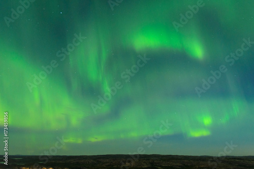 The Aurora in the sky above the hills at night . © Moroshka